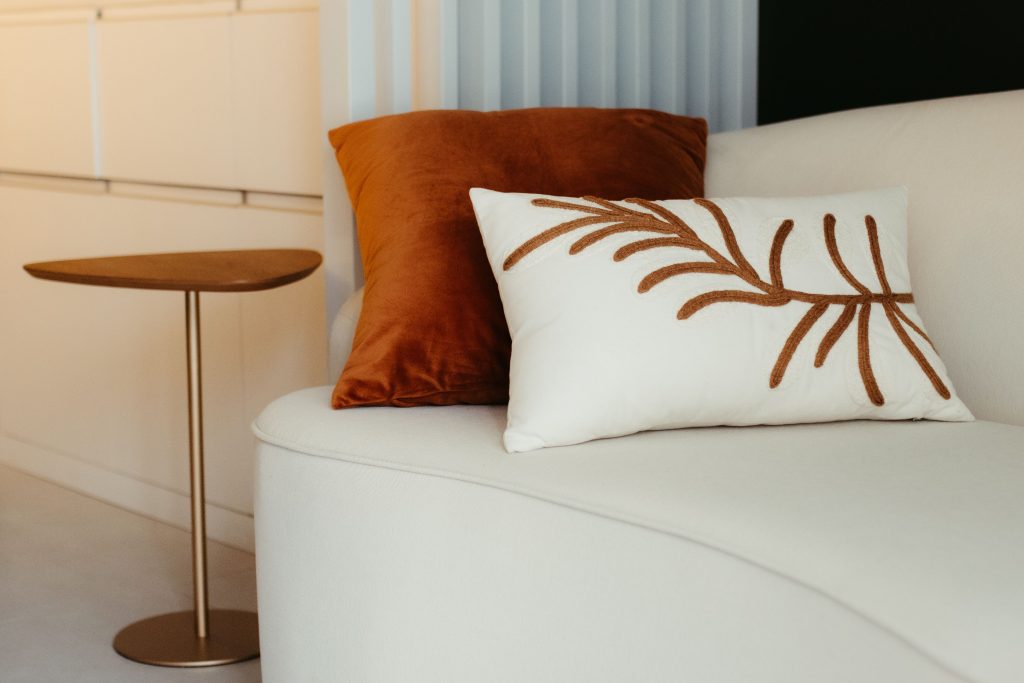 Elegant modern living room with stylish pillows on a cozy sofa beside a minimalist table.